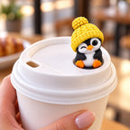 Winking Penguin with yellow hat on a coffee cup lid